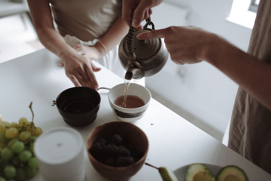 Tea poured from a cast kettle into two bowls — photo by alleksana on Pexels