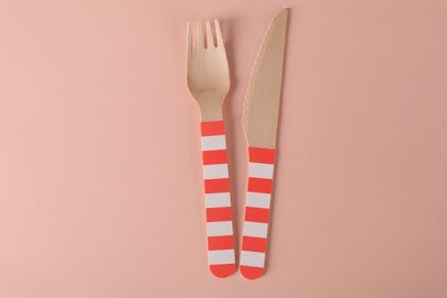 Close-Up Shot of Wooden Fork and Knife on a Pink Surface