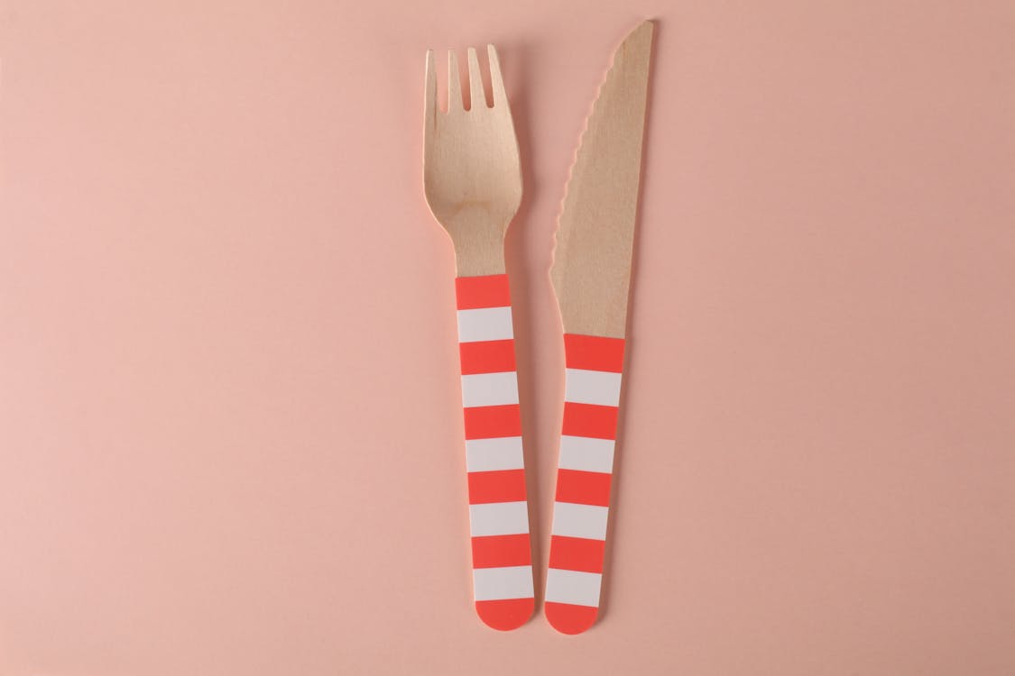 Close-Up Shot of Wooden Fork and Knife on a Pink Surface