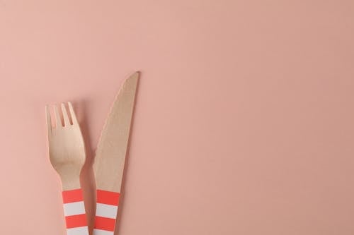 Free Close-Up Shot of Wooden Fork and Knife on a Pink Surface Stock Photo
