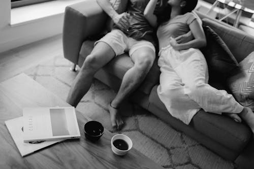 Grayscale Photo of Couple Sitting on a Sofa 