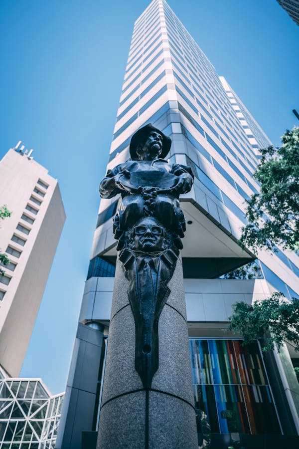 From below of old metal sculpture placed on square near high modern building in Uptown Charlotte
