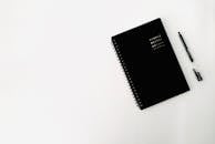 Black copybook and pen on table