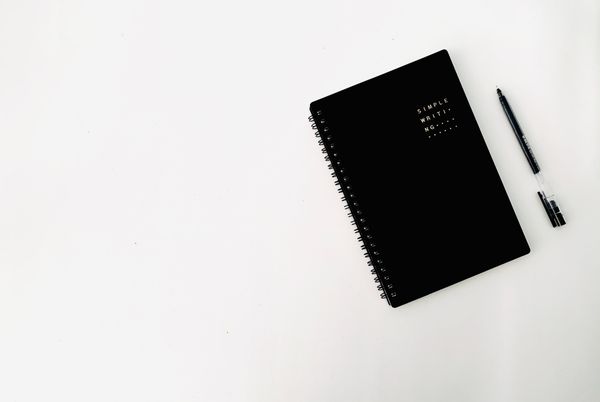 Black notebook and pen on a white desk