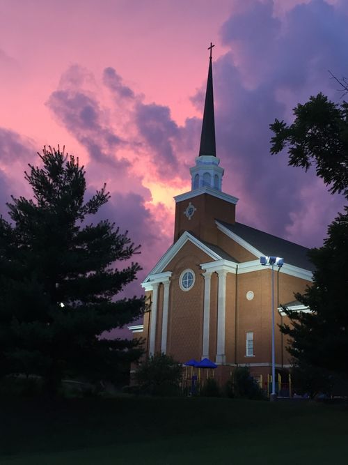 Free A beautiful church steeple against a dramatic pink and purple sunset sky. Stock Photo