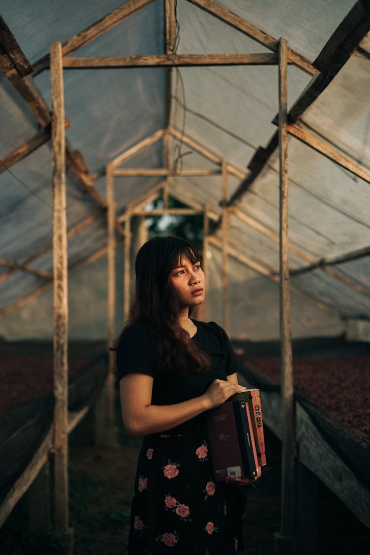 A Woman In Black Top And Floral Skirt Holding Books 