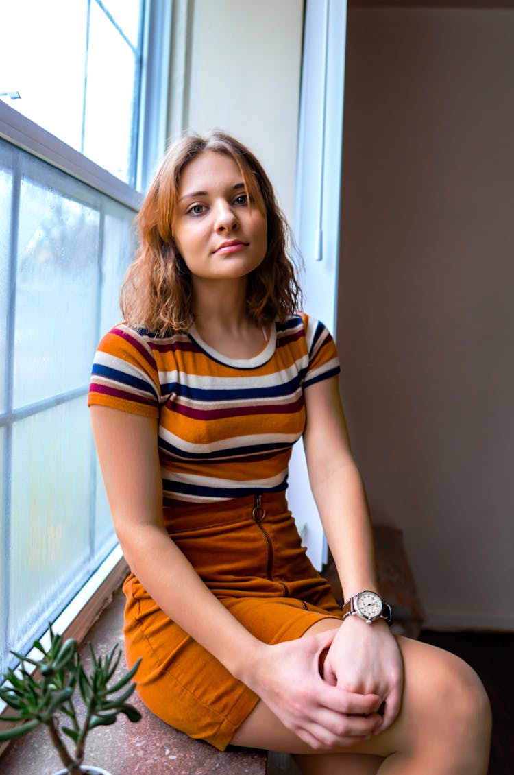 Woman In Striped T Shirt And Yellow Skirt On Window