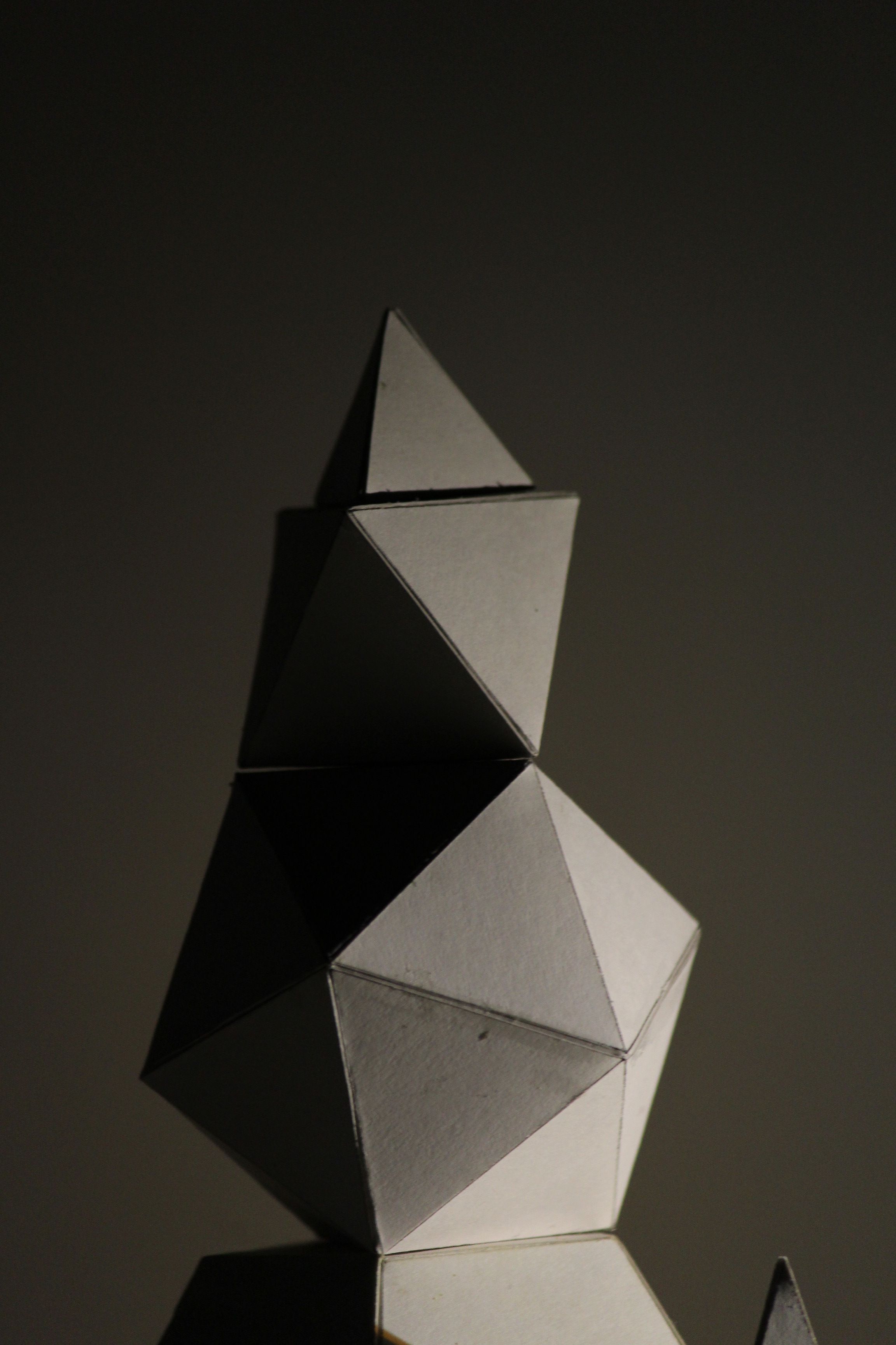 Intricate paper sculptures with geometric shapes highlighted in low light.