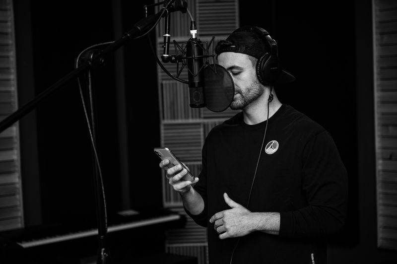 Independent musician recording vocals and creating content inside a studio