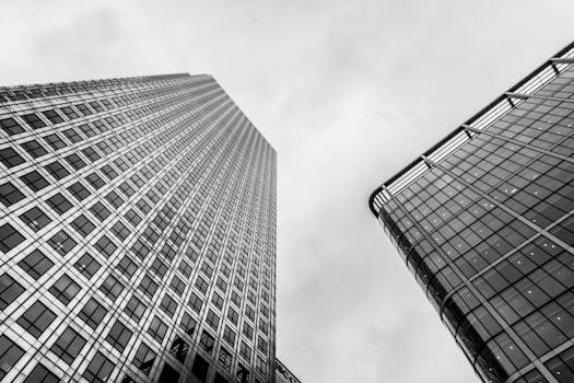 在戏剧性的多云天空下，低角度仰望这座玻璃立面的现代摩天大楼