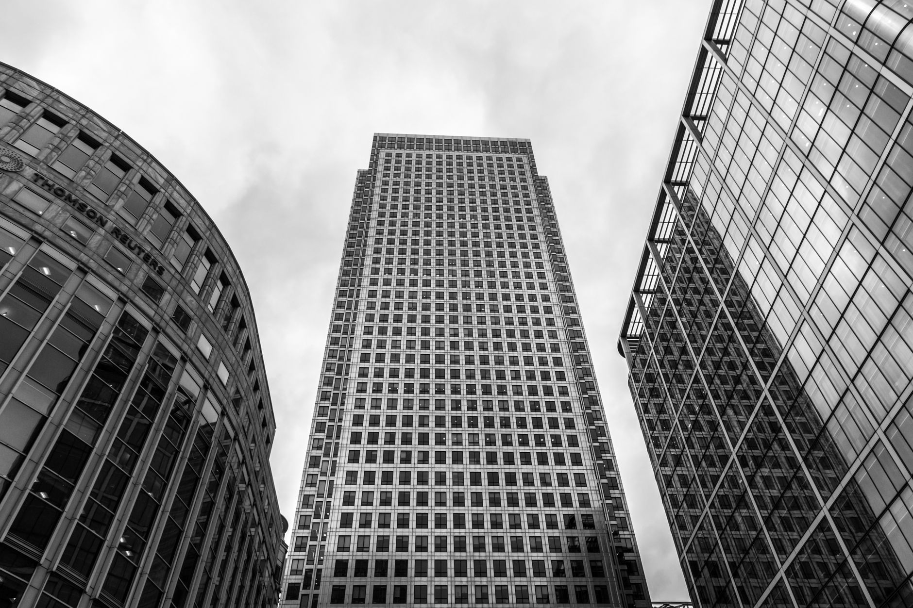 Low angle view of modern skyscrapers in Canary Wharf, London, captured in black and white.