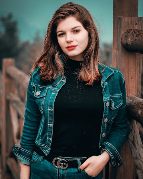 Relaxed young woman standing near wooden fence in countryside