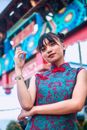 一位年轻女子身着传统亚洲服装，在户外城市环境中自信摆姿，展现了现代风格与文化