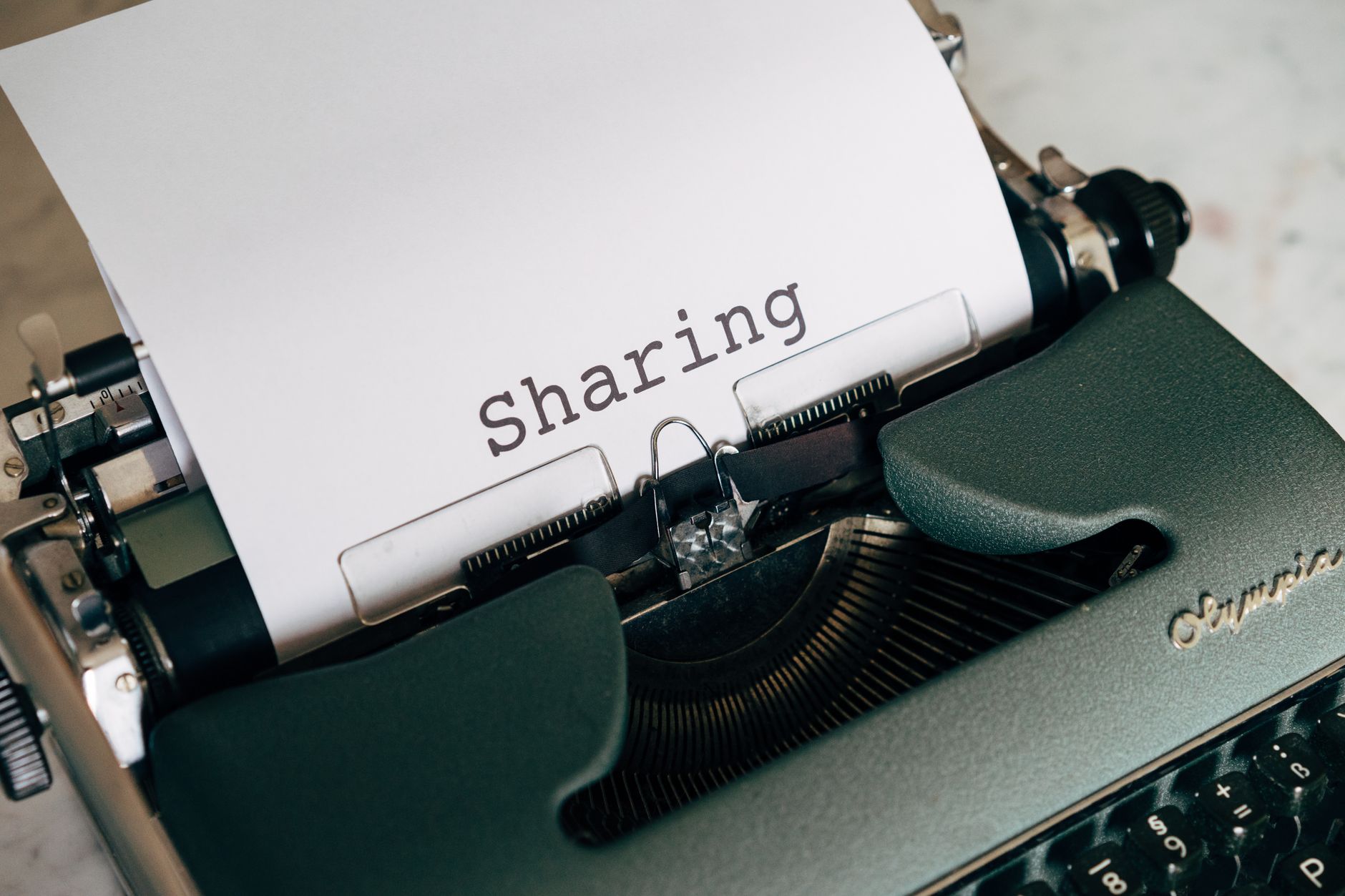 Close-up of a vintage typewriter with paper showing the word 'Sharing', conveying retro communication.