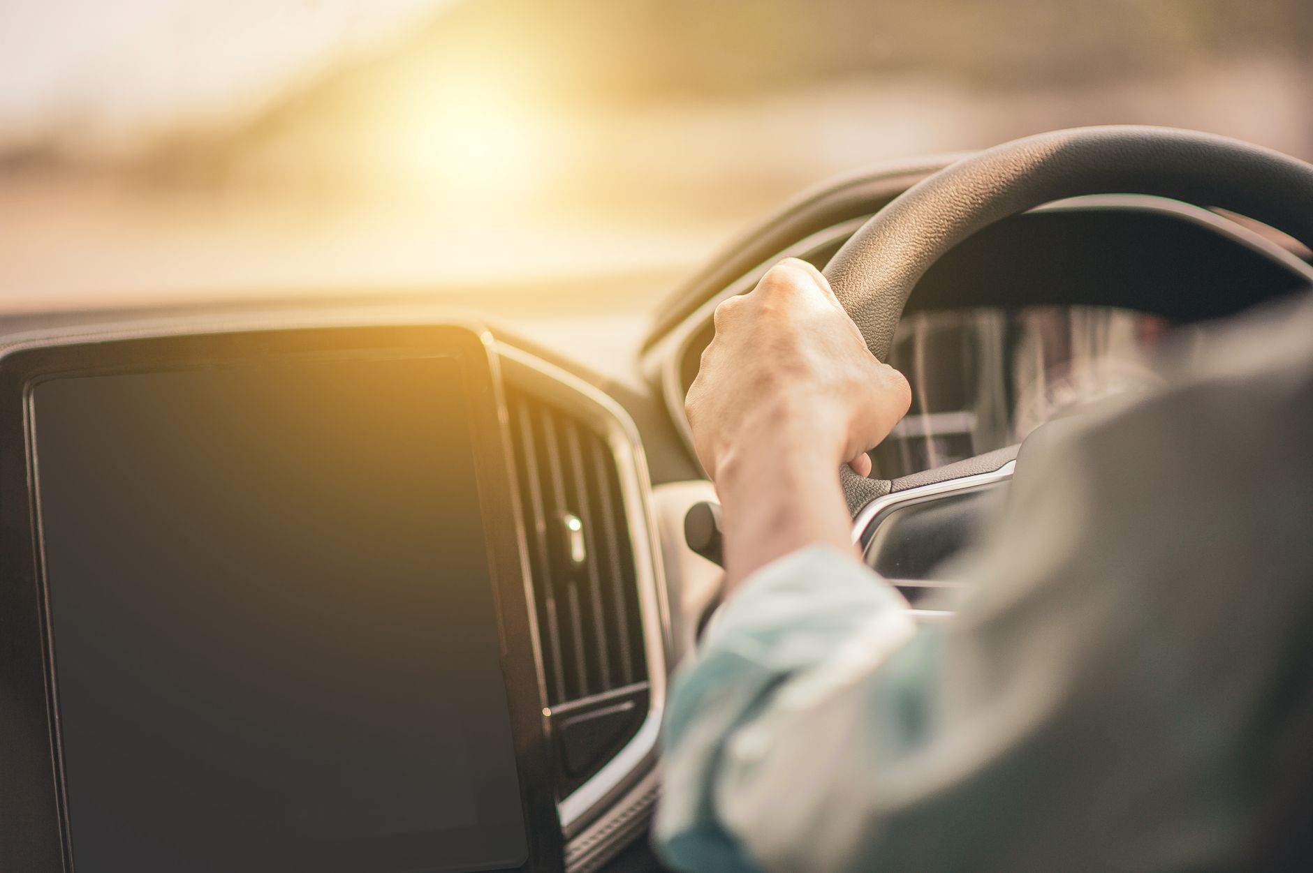 Driver gripping the steering wheel firmly with hands at proper position while driving, demonstrating control during a tire blowout