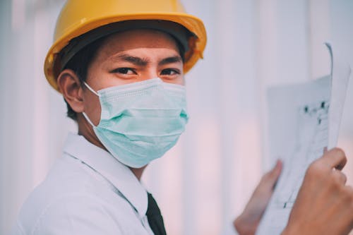 Free Man Wearing a Mask Holding a Blueprint Stock Photo