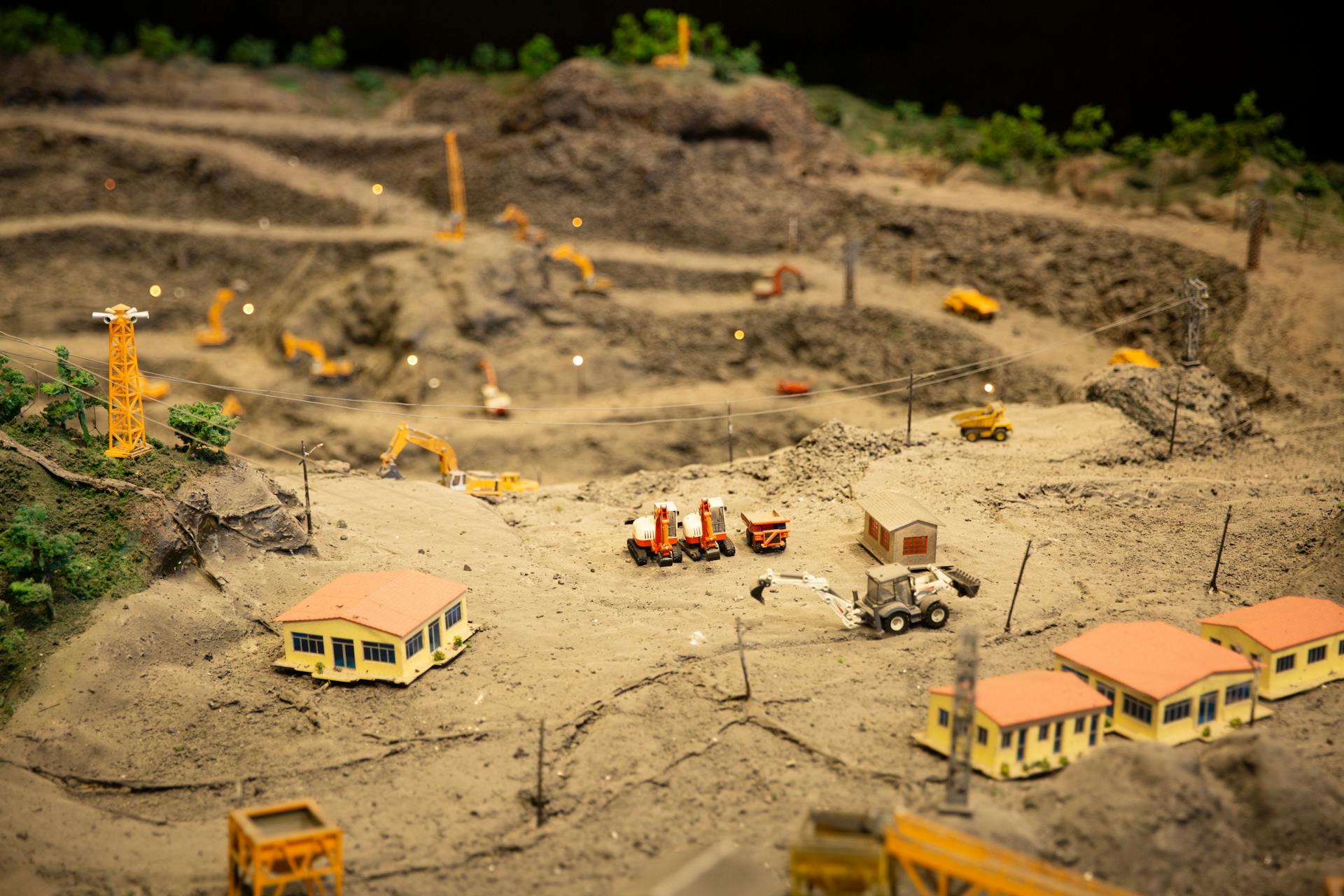 High-angle view of a detailed miniature construction site diorama with toy vehicles and buildings.