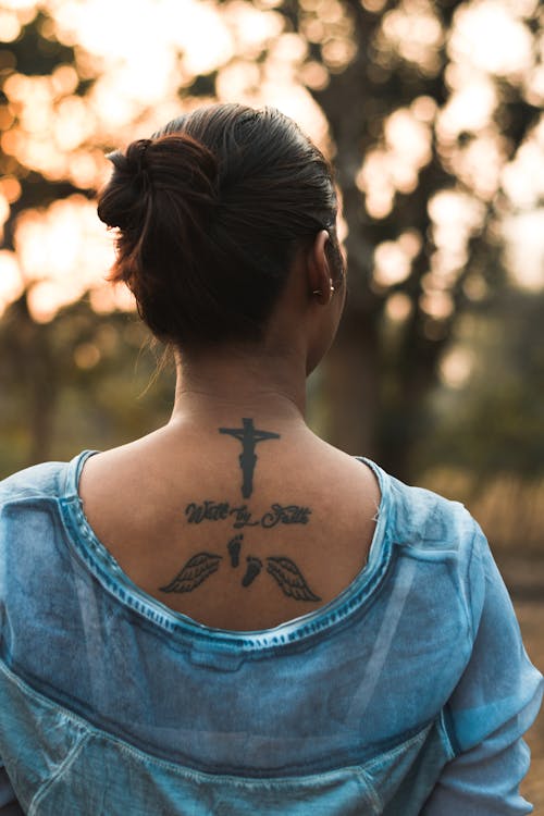 Unrecognizable young tattooed woman admiring nature in park