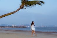Young Asian woman walking along sandy beach in evening