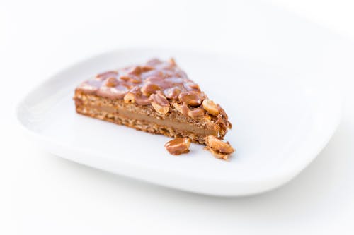 A Slice of Caramel Cake With Chocolate Coated Nuts