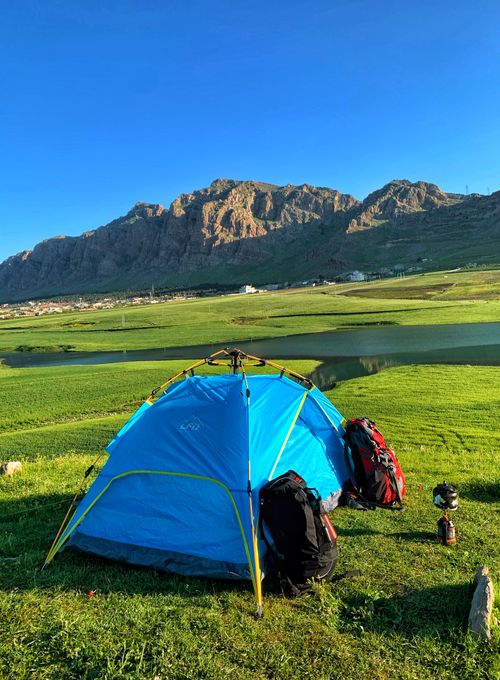 Free Blue camping tent with backpacks against mountain backdrop in Ranya, Iraq. Stock Photo