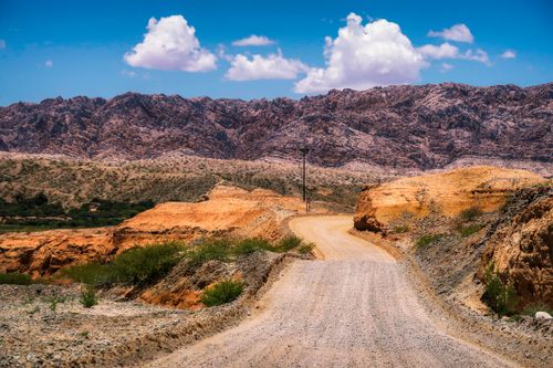 Free Picturesque scenery of empty rural road going through wild valley with colorful formations and rocky mountains against blue sky on sunny day Stock Photo