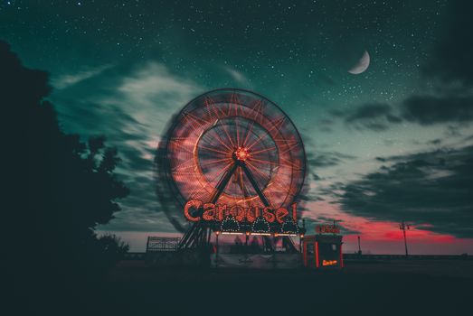 夜晚，发光的摩天轮以星空和新月为背景