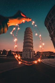 Artistic twilight view of the Leaning Tower of Pisa with string lights framing the landmark, creating a magical ambiance.