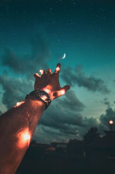 一只手伸向星空中的月牙，营造出神秘的氛围