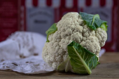 Free Close-up of a fresh cauliflower head on a rustic table, ideal for healthy eating themes. Stock Photo