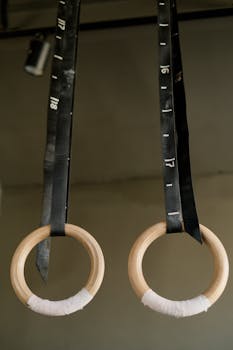 Close-up of wooden gymnastic rings hanging indoors, ready for training.
