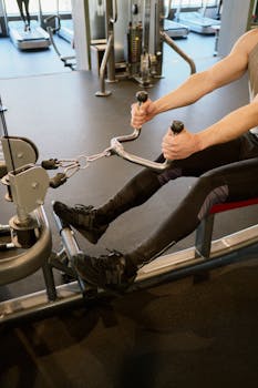 Adult male working out on a rowing machine in a modern fitness gym, emphasizing strength training.