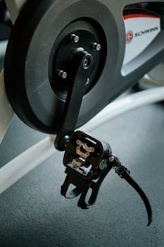 Detailed view of an exercise bike pedal and crank in a fitness center.