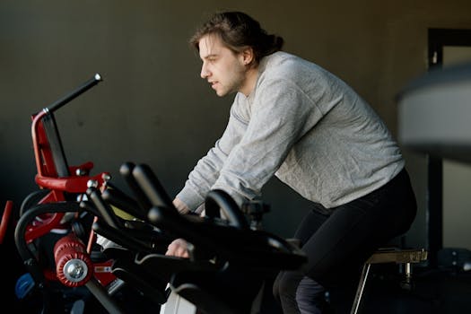 Man engaged in a focused workout on a stationary bike in a gym setting.