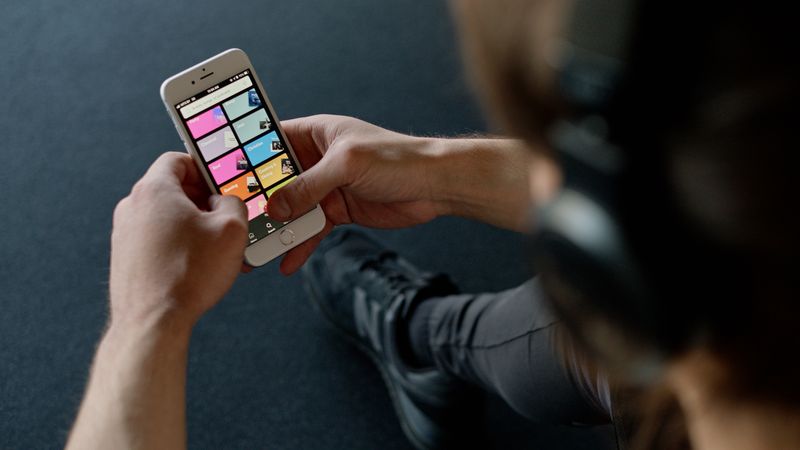 Close-up of a person listening to music on a smartphone while at the gym, focusing on a streaming playlist app.