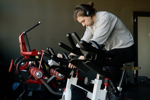 Man in gym on exercise bike wearing headphones, focused on fitness training.