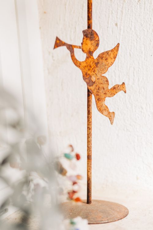Free A vintage rusted metal angel figurine with trumpet in a warm indoor setting. Stock Photo