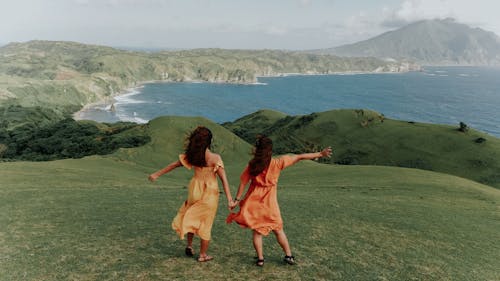 Women Standing on the Green Mountain Near the Ocean