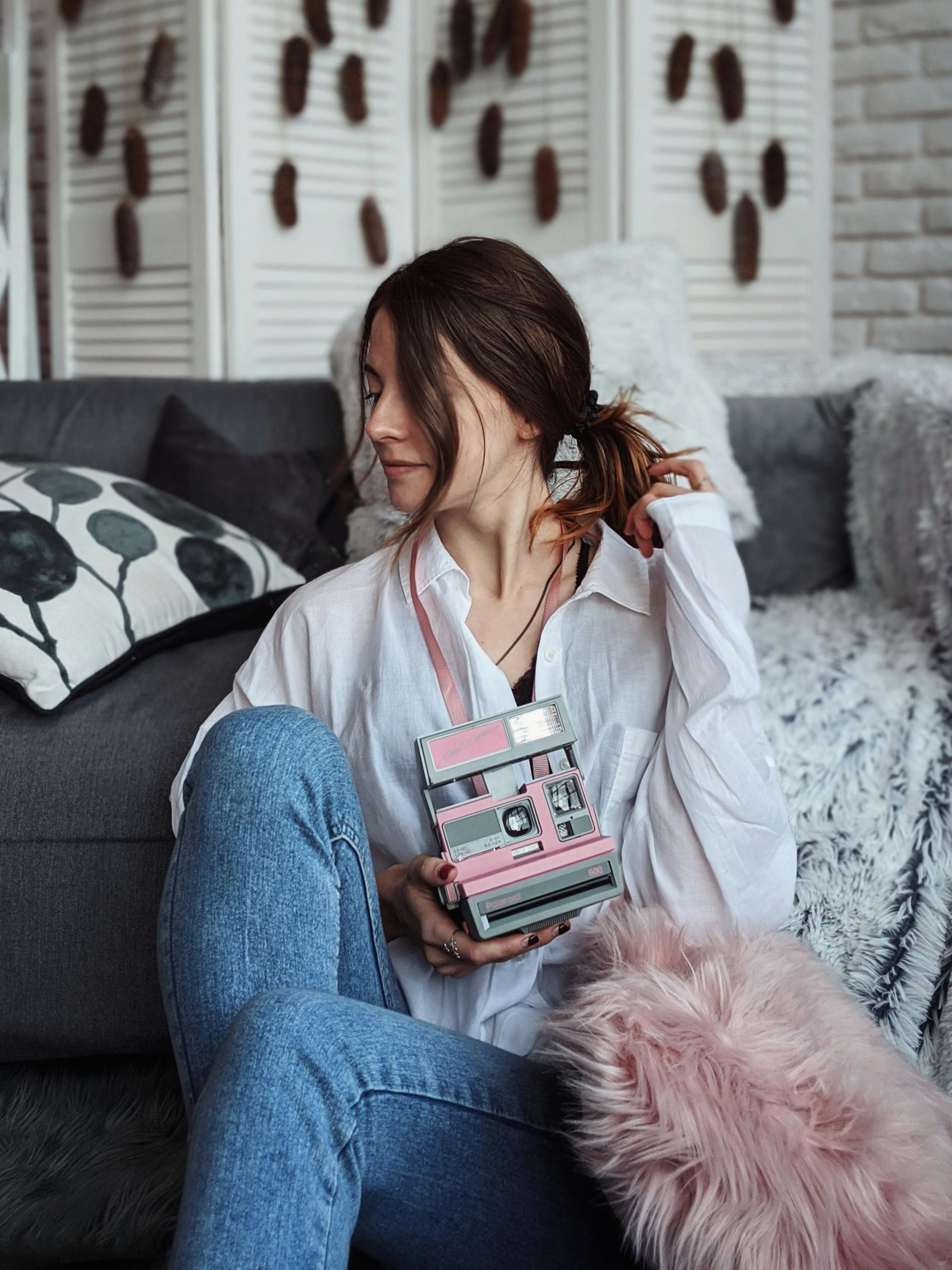 Young woman in a cozy indoor setting, holding a vintage camera. Casual and stylish ambiance.