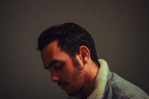 Free Bearded calm man with hairstyle wearing warm denim coat looking down in shadow on gray background Stock Photo