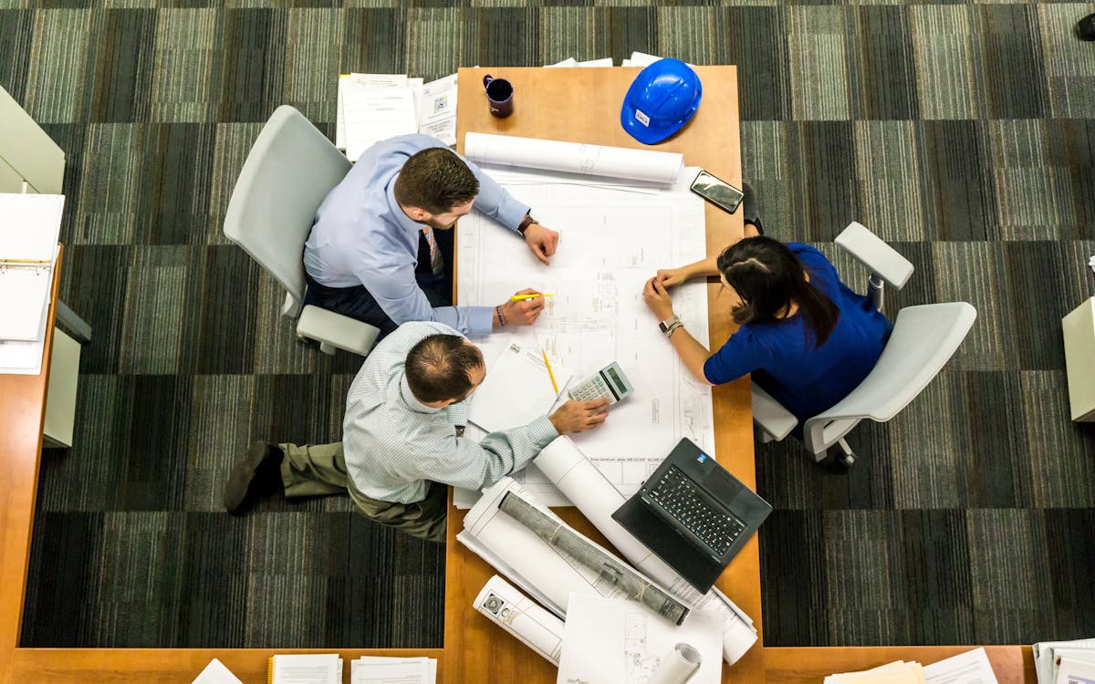 Three People Sitting around Table discussing a project