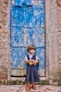 在印度，一名穿着校服的年轻女孩独自站在一扇古老的蓝色门旁
