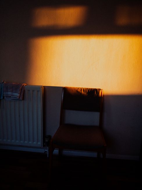 Moody chair photo with warm sunlight and shadow play on a room wall.