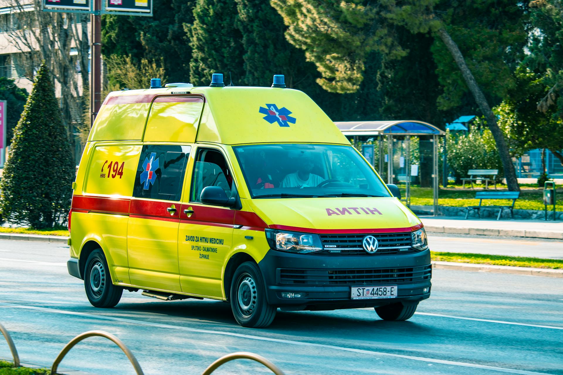 A bright yellow ambulance moves swiftly on a city street, providing emergency services.