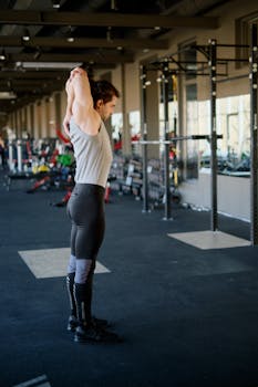 Caucasian male doing stretching exercises in an indoor fitness gym with modern equipment.