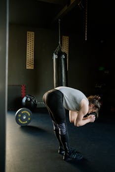 Man takes a break in a dimly lit gym, surrounded by equipment and weights.