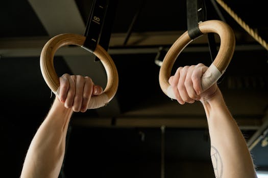 Hands gripping gymnastic rings in a fitness gym, displaying strength and focus.