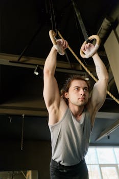 A man performs a workout using gymnastic rings in a fitness center, emphasizing strength and focus.