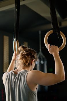 Male athlete performing strength training on gymnastic rings indoors.