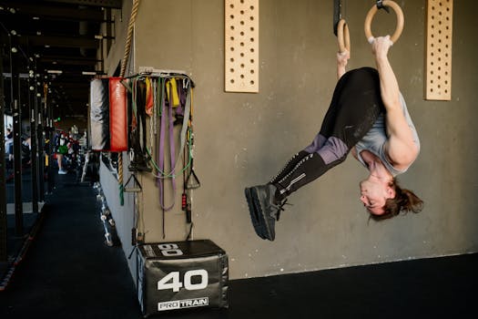 Man performing an upside-down exercise on gymnastic rings in a modern fitness gym.